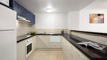 Una cocina moderna con armarios blancos, encimera negra y salpicadero de azulejos.