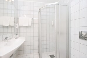 A bathroom with a shower, a sink, and a towel rack. - P-hotels Oslo (Oslo)