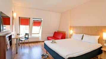 Ein Hotelzimmer mit Bett, Schreibtisch, Stuhl und Fernseher.
