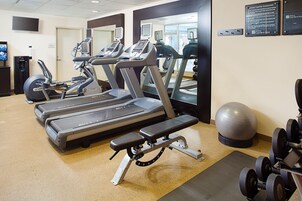 A fitness center with treadmills, ellipticals, a stationary bike, and free weights.