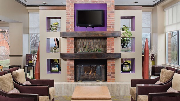 A living room with a fireplace, comfortable seating, and a flat-screen TV mounted above the fireplace.
