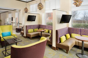 A hotel lobby with seating areas, a flat-screen TV, and a large window. - Hilton Garden Inn Hartford North/Bradley Int'l Airport (Windsor)