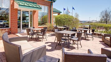 An outdoor patio area with wicker furniture and a brick building in the background.