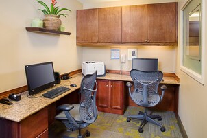A small office space with a desktop computer, two office chairs, a printer, and a telephone.