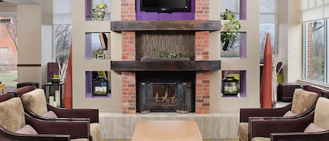 A modern living room with a fireplace, comfortable seating, and a flat-screen TV mounted above the fireplace.