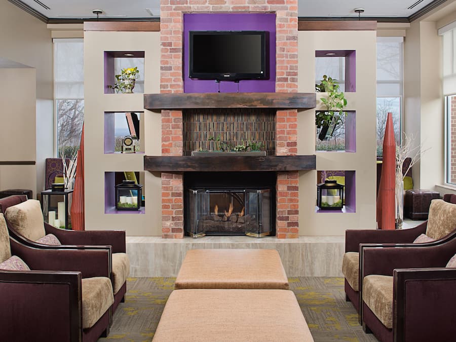 A modern living room with a fireplace, comfortable seating, and a flat-screen TV mounted above the fireplace.