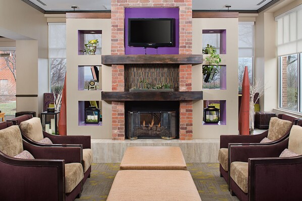 Una sala de estar moderna con chimenea, asientos cómodos y un televisor de pantalla plana montado sobre la chimenea.