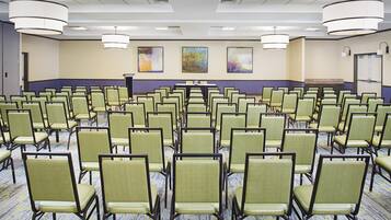 A conference room with rows of chairs, a podium, and abstract paintings on the wall.