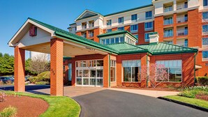 A multi-story hotel with a brick facade, green roof, and a covered entrance.
