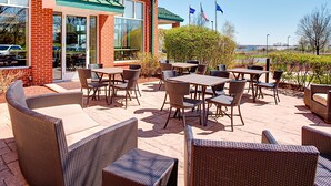 An outdoor patio area with wicker furniture and a brick building in the background.