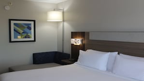 Une chambre d’hôtel avec un lit, une table de chevet, une lampe et un tableau encadré au mur.