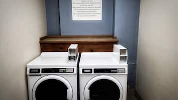 Un área de lavandería para huéspedes con dos lavadoras Maytag, un banco de madera y un letrero con instrucciones para el uso de la lavandería.