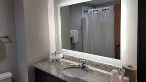 Une salle de bain avec un comptoir en granit, un lavabo, un miroir et un rideau de douche.