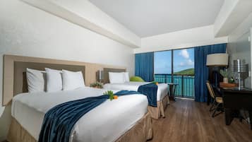 A hotel room with two beds, a balcony with a view, a desk, and a chair.