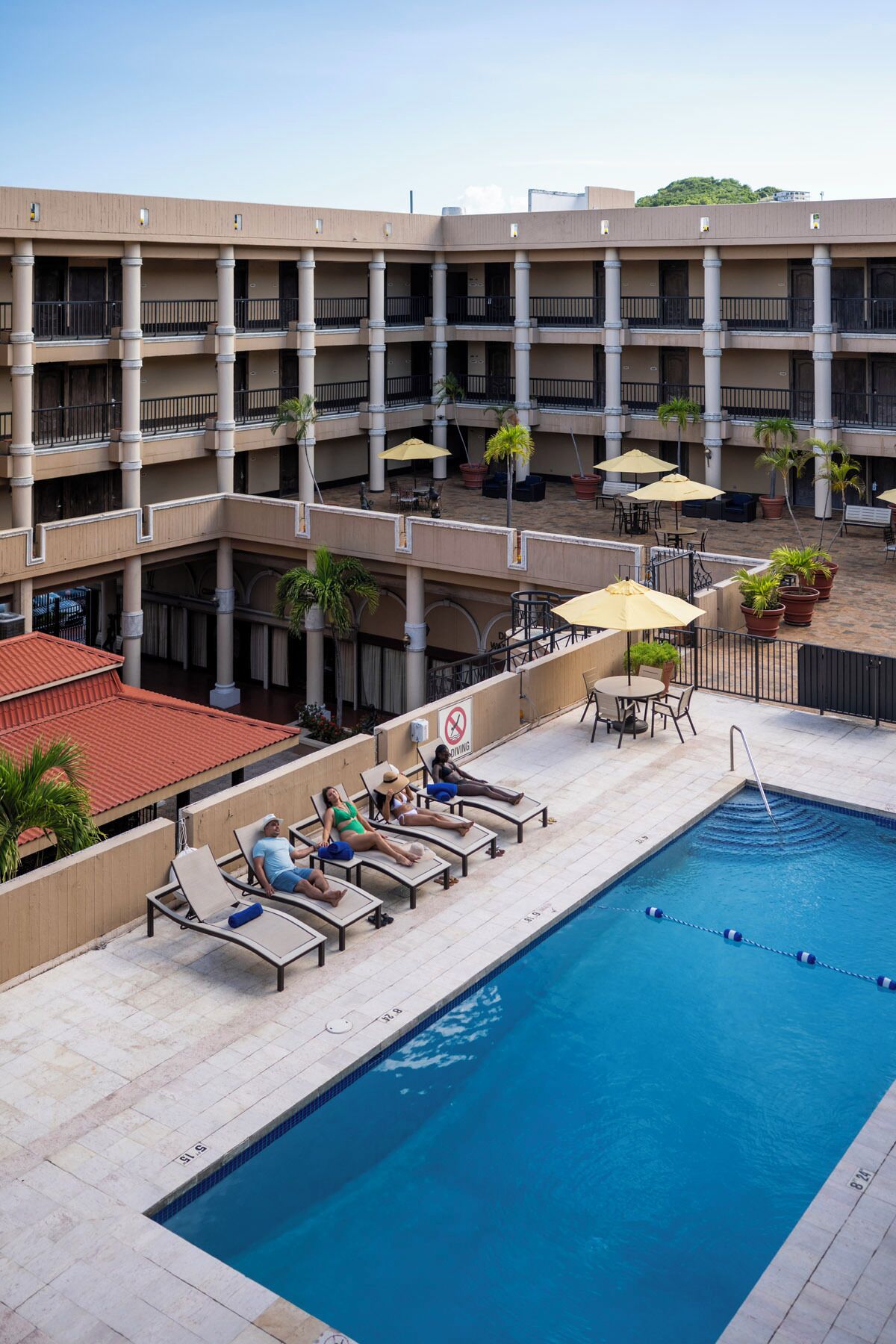 A hotel pool area with lounge chairs, umbrellas, and a pool.