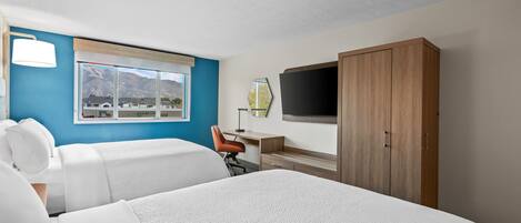 A hotel room with two beds, a desk, a chair, a TV, and a wardrobe.