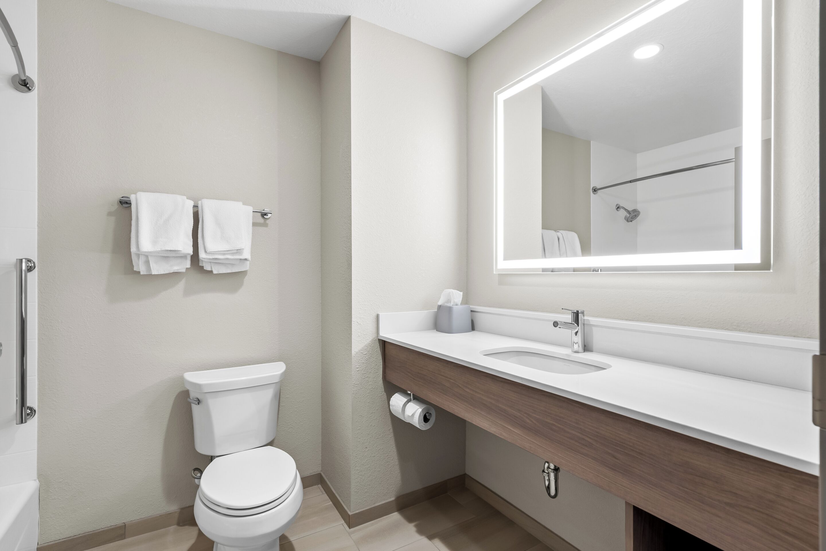 A modern bathroom with a toilet, sink, and mirror.