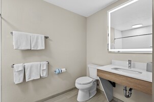Un baño moderno con inodoro, lavamanos y espejo.