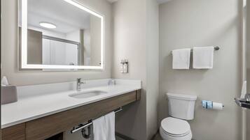A modern bathroom with a large mirror, a sink, a toilet, and two towels hanging on the wall.