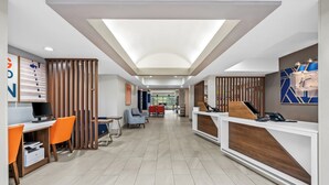 Un hall d’hôtel moderne comprenant un comptoir d’accueil, un espace salon et un poste informatique.