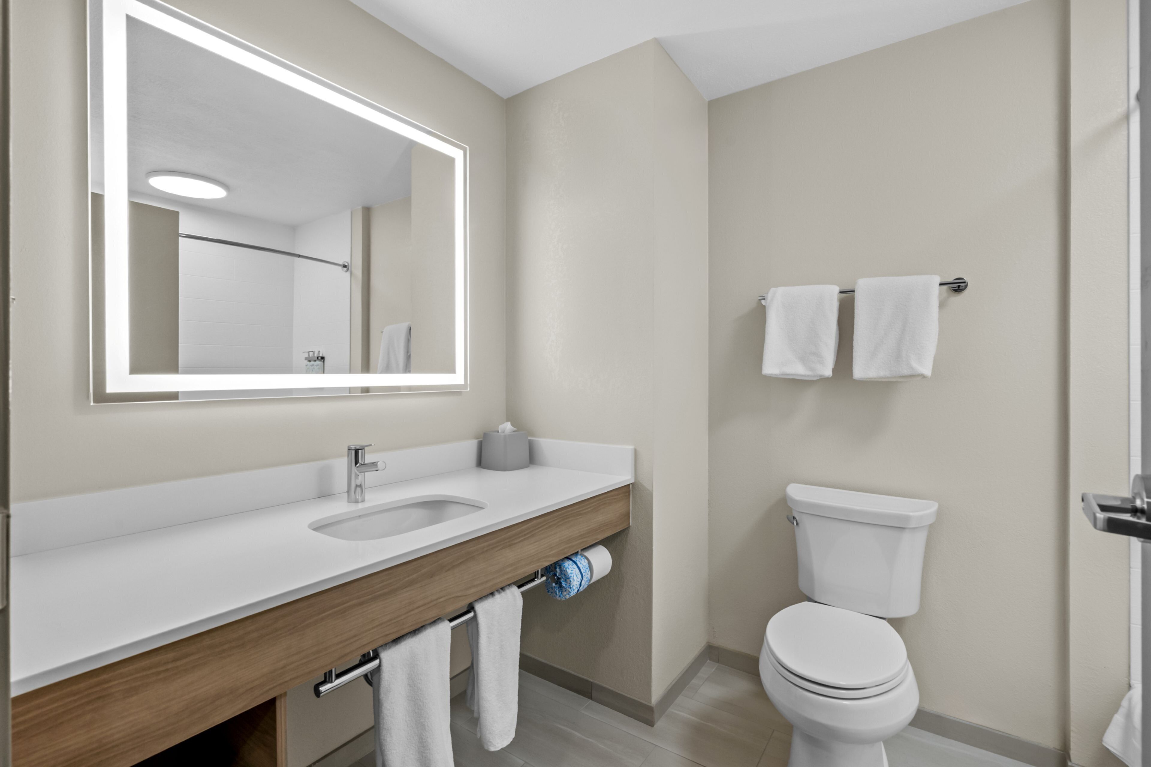 A modern bathroom with a white sink, mirror, and toilet.