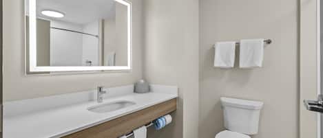 A modern bathroom with a white sink, mirror, and toilet.