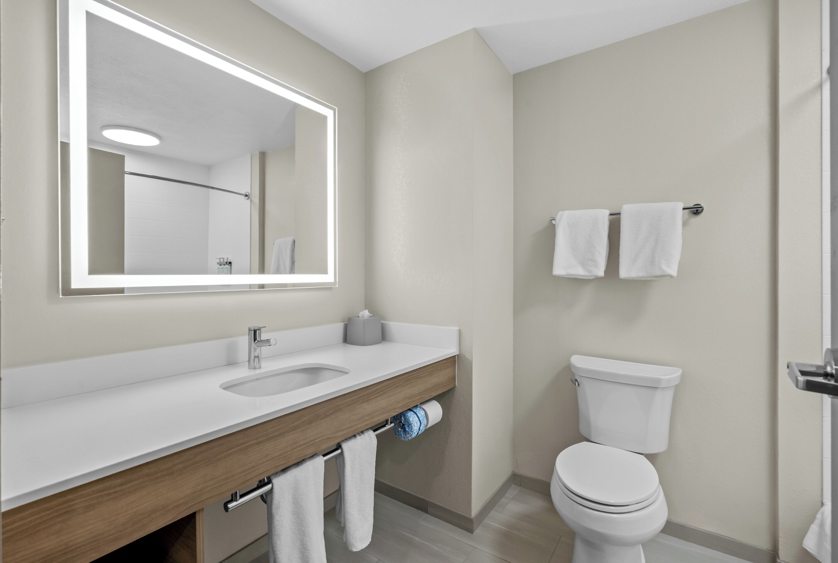 Une salle de bain moderne avec un lavabo blanc, un miroir et des toilettes.