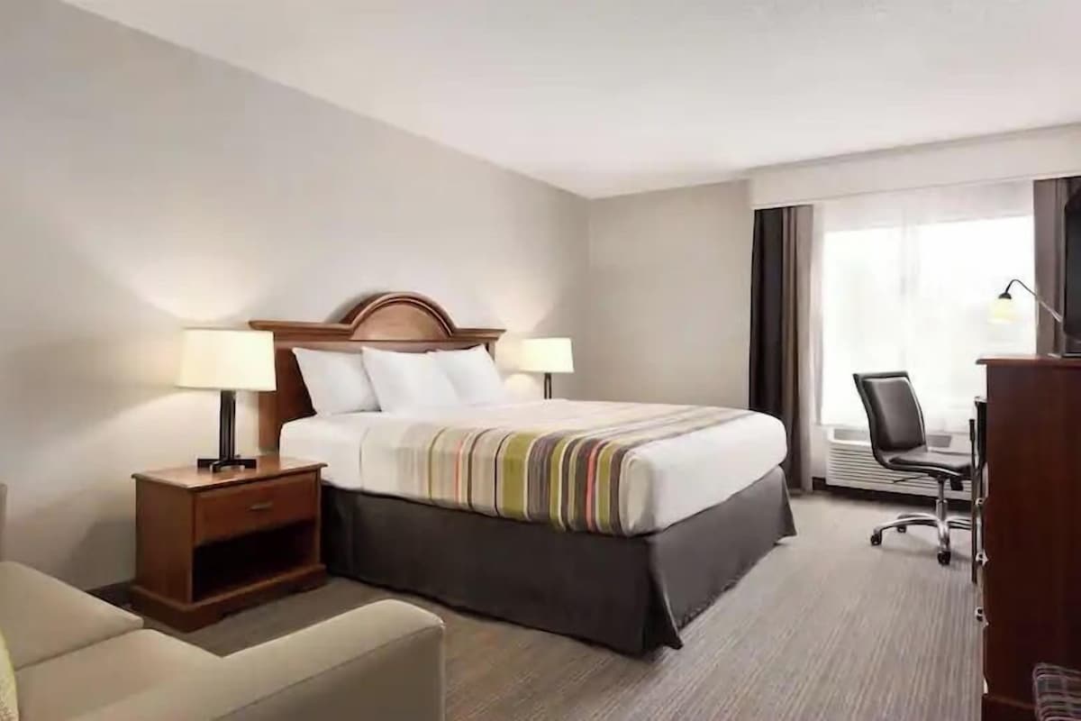 Habitación de hotel con cama, dos mesitas de noche, un escritorio y una silla.