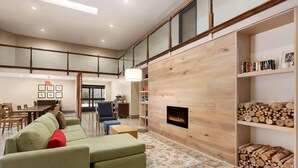 A spacious living room with a fireplace, a sofa, a dining area, and a bookshelf. - Country Inn & Suites by Radisson, Dahlgren-King George, VA (King George)