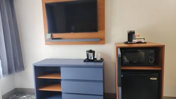 Camera d'albergo con TV a schermo piatto fissata al muro, macchina del caffè e forno a microonde su un mobile in legno.