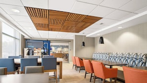 A modern dining area with tables and chairs, a patterned wall, and a ceiling with wooden slats.