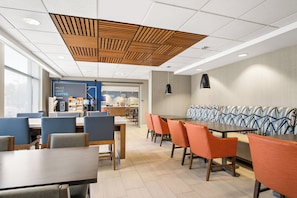 A modern dining area with tables and chairs, a patterned wall, and a ceiling with wooden slats.