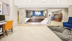 A spacious lobby with a reception desk, a blue sofa, and a bookshelf. - Holiday Inn Express Hotel & Suites Ocean City by IHG (Ocean City)