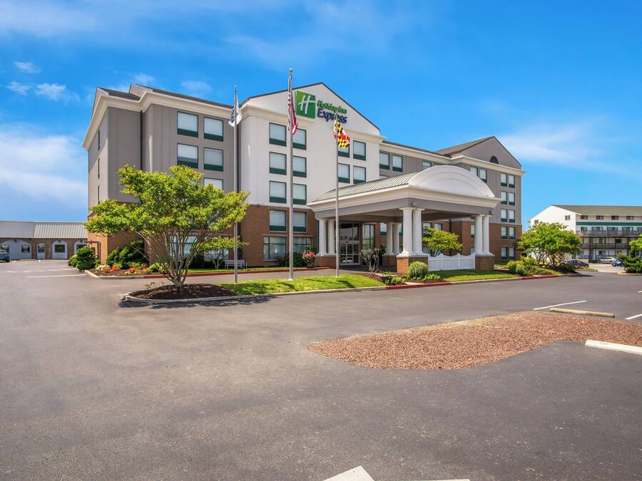A Holiday Inn Express hotel with a central entrance, flagpoles, and a landscaped area.