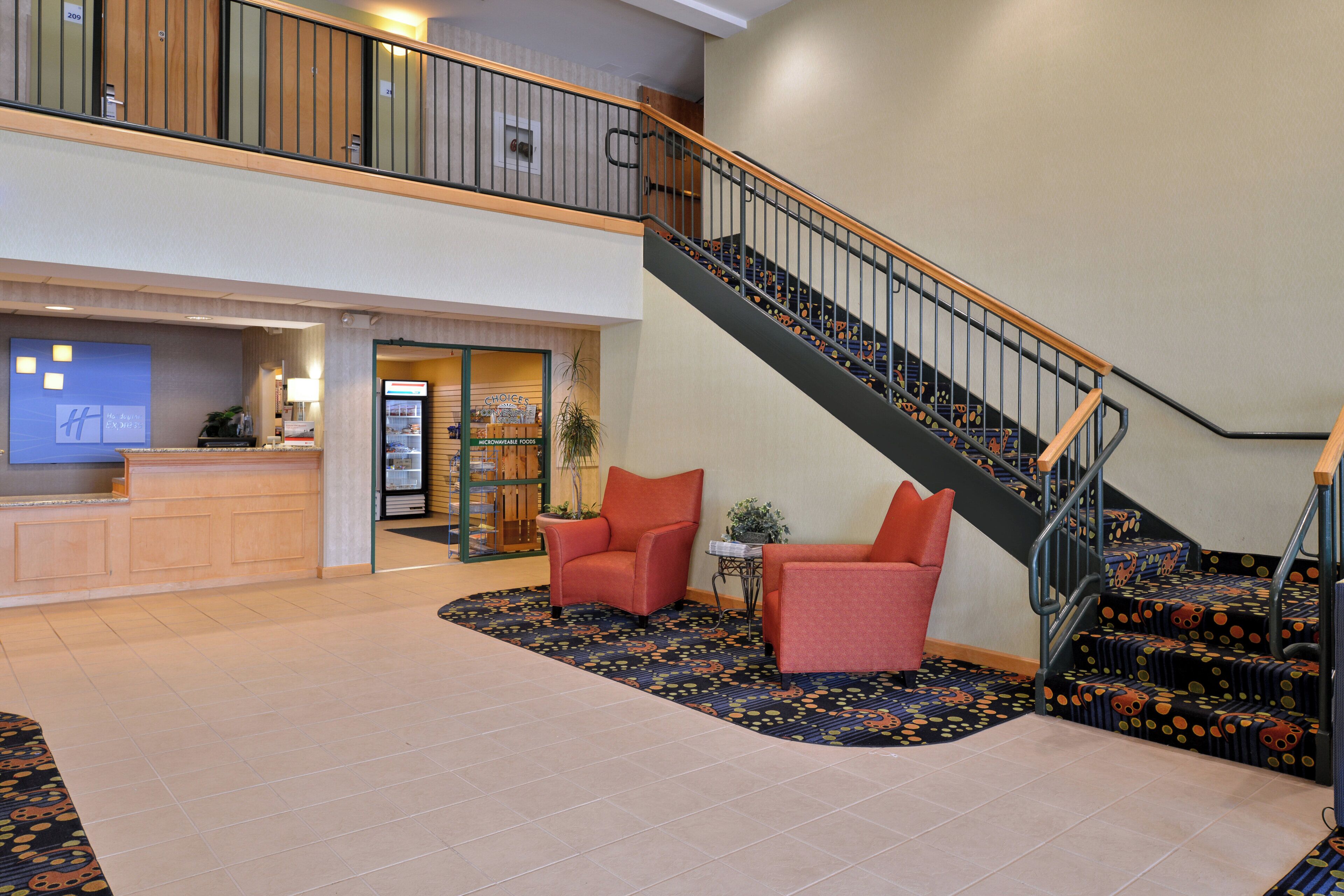 A hotel lobby with a reception desk, a staircase, and seating area.