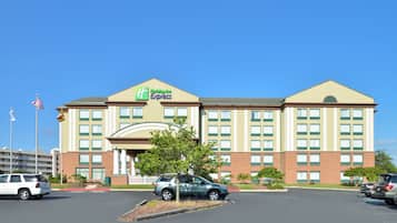 Edificio de Holiday Inn Express con entrada central, varias ventanas y aparcamiento con coches.