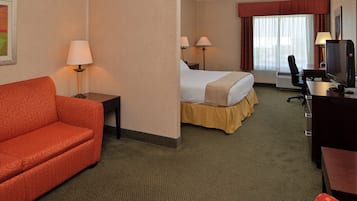 Une chambre d’hôtel comprenant un lit, un bureau, une télévision, une chaise et un canapé.