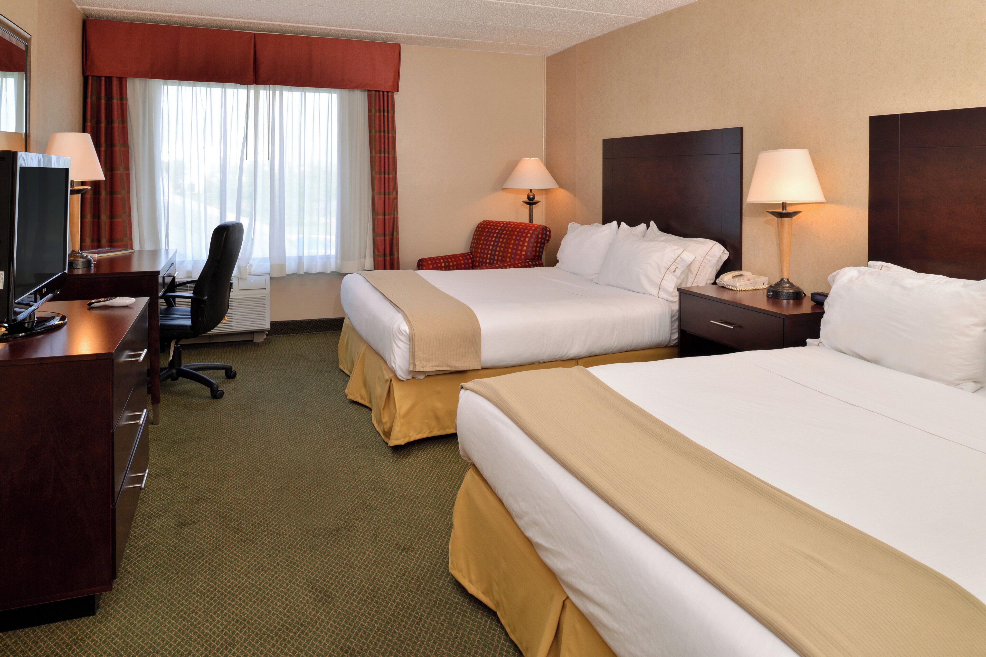 Een hotelkamer met twee bedden, een bureau, een stoel, een televisie en een telefoon.