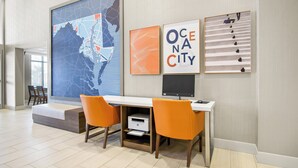 A modern office space with a large map, framed artwork, and a desk with two orange chairs.