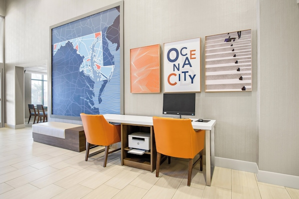 Un espacio de oficina moderno con un mapa grande, obras de arte enmarcadas y un escritorio con dos sillas naranjas.