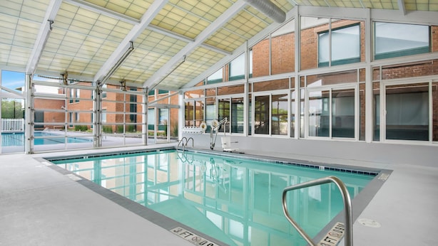 An indoor swimming pool with clear markings, a covered roof, and a view of a brick building outside.