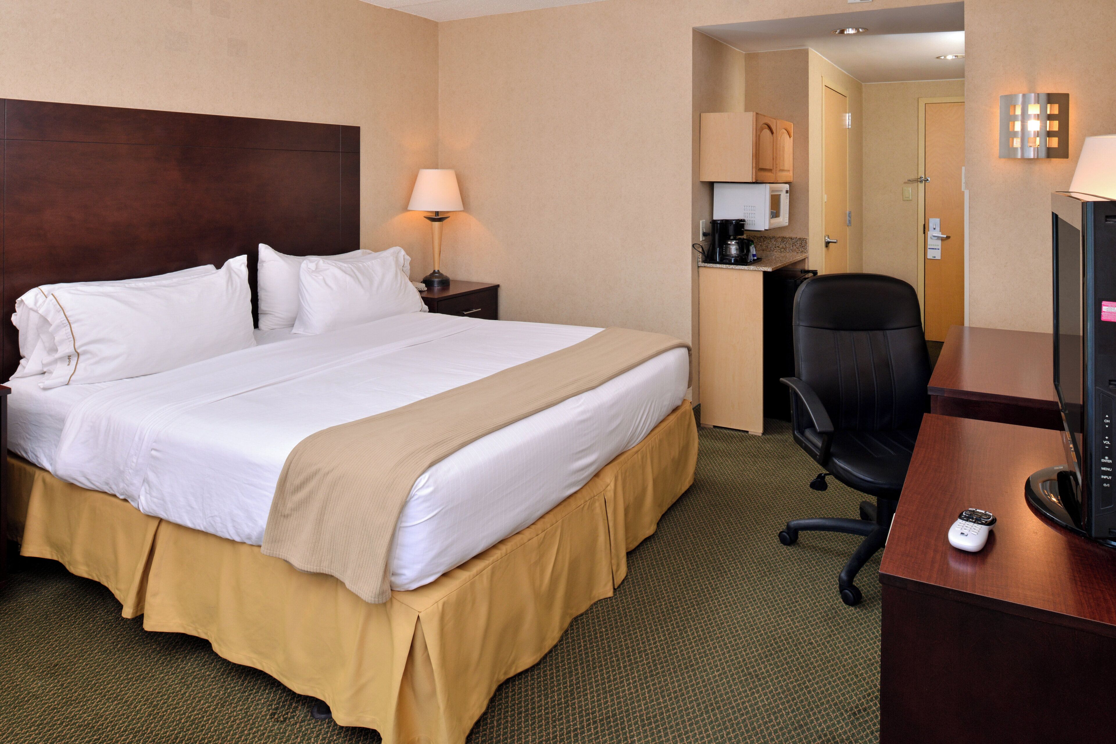 Una habitación de hotel con una cama, un escritorio, una silla, un televisor y una cafetera.