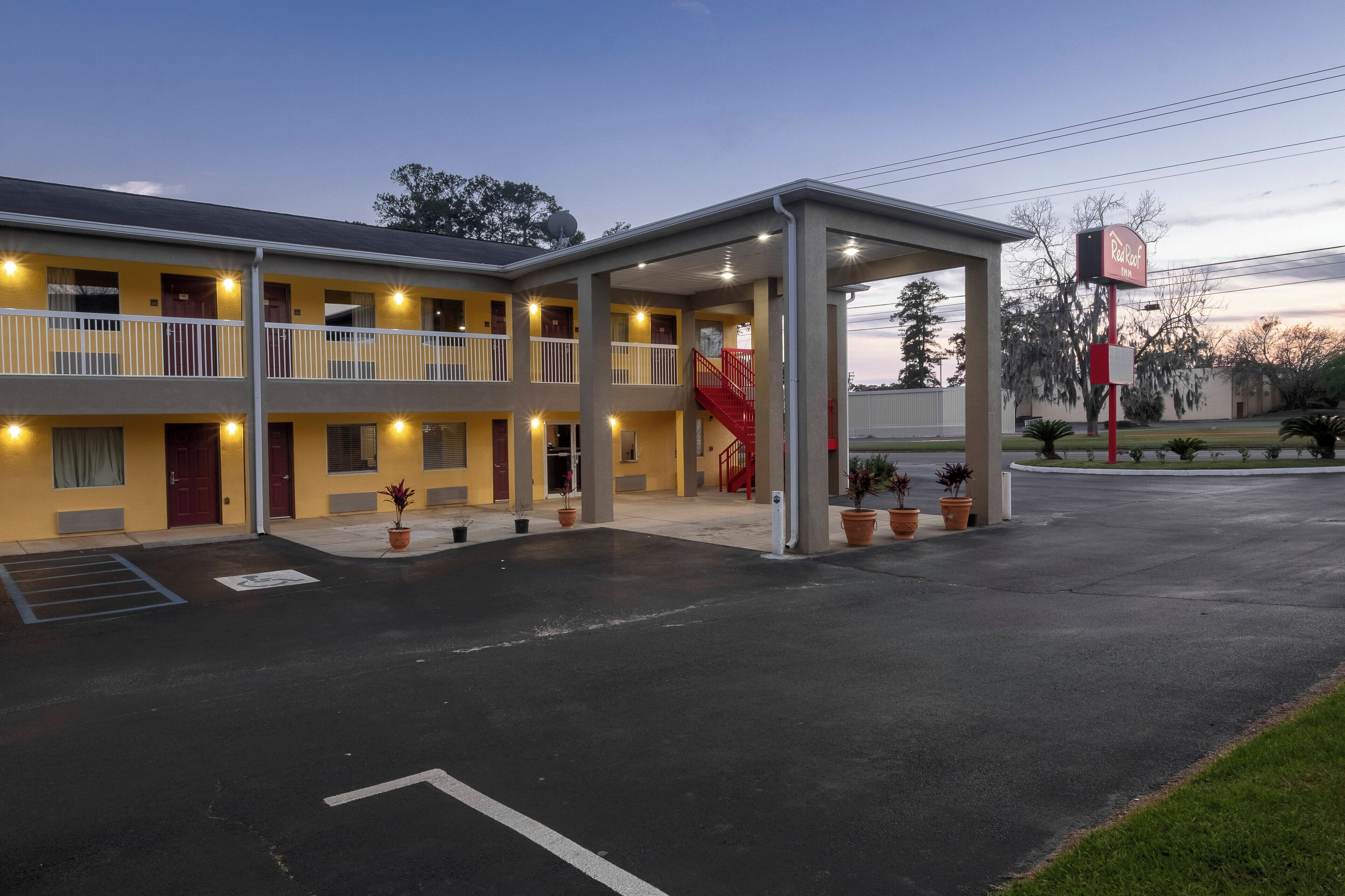 A motel with a covered parking area, multiple balconies, and a red staircase.