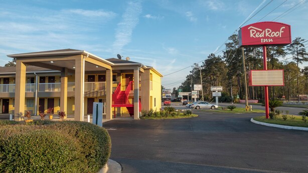 Een Red Roof Inn met een overdekte parkeerplaats en een rode trap die naar de ingang leidt.