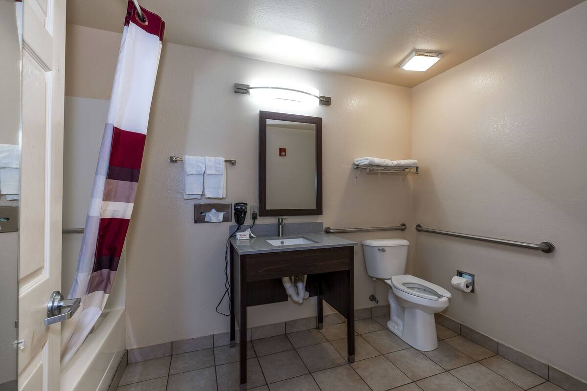 Ein Badezimmer mit Waschbecken, Spiegel, Toilette und Duschvorhang.