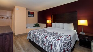 Una habitación de hotel con cama, lámparas de noche, una mesita, un espejo y un calefactor de pared.