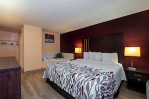 Una habitación de hotel con cama, lámparas de noche, una mesita, un espejo y un calefactor de pared.