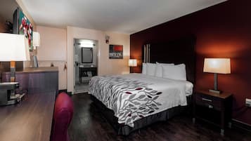 Una habitación de hotel con una cama, mesitas de noche, un escritorio y una silla.