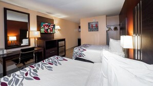 Een hotelkamer met twee bedden, een bureau, een televisie en een koelkast.