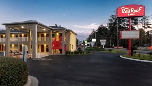 Een Red Roof Inn met een gebouw van twee verdiepingen, een overdekte parkeerplaats en een rood bord.